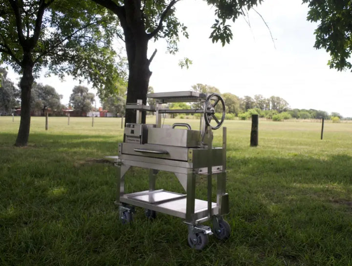 Tagwood Freestanding "Mini" Santa Maria Style Grill features compact design with four cooking zones, including height-adjustable main grate and interchangeable griddle, built from durable #304 stainless steel for authentic gaucho cooking experience in a portable format.