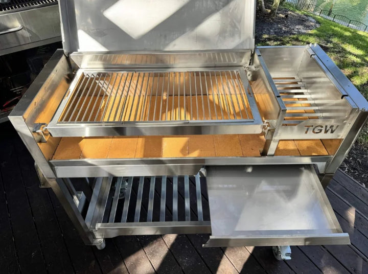 Tagwood Freestanding Santa Maria Style Grill – Stainless Steel, premium 304 stainless steel construction, 705 sq. in. cooking surface, dual preset grate positions, brasero firebox for temperature control.