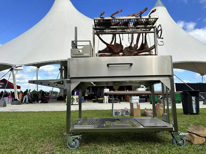 Tagwood Santa Maria Style Wood Grill featuring #304 stainless steel construction, adjustable main grate, secondary grate, interchangeable griddle, and S-shape meat hooks for versatile open-fire cooking.