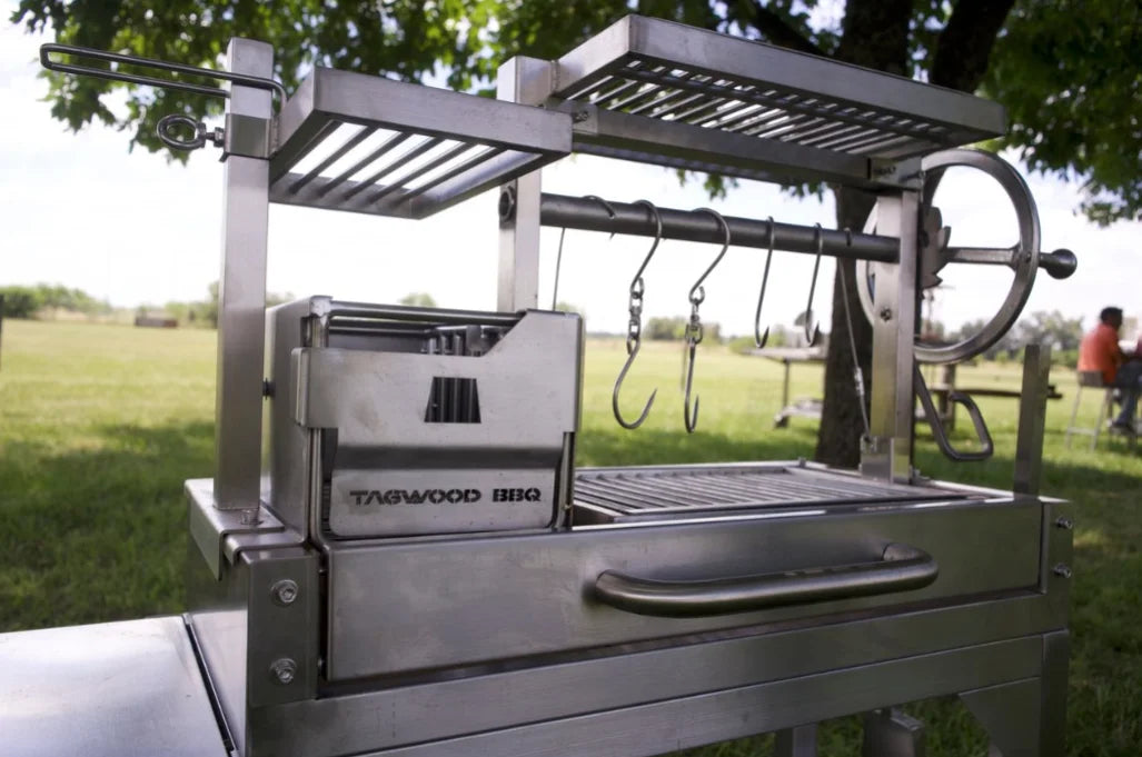 Tagwood Freestanding "Mini" Santa Maria Style Grill: Compact stainless steel grill with four distinct cooking zones, featuring height-adjustable main grate, interchangeable griddle, secondary grate, and S-shape hooks for hanging meat.