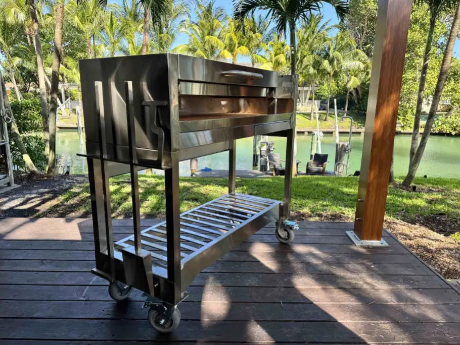 Tagwood Freestanding Santa Maria Style Grill – Stainless Steel; premium 304 stainless steel construction, featuring 705 sq. in. cooking surface, dual preset grate positions, and brasero firebox for authentic Argentine-style live-fire cooking, complete with integrated drainage system, heavy-duty casters, and included stainless steel tools and bottle opener.