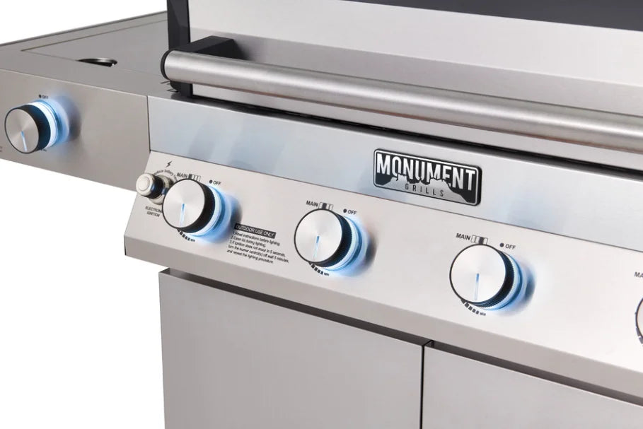Monument Grills Denali Series D405 Stainless Steel Gas Grill featuring four high-performance burners, clearview lid for effortless visibility, Bluetooth smart control, and color-changing LED backlit knobs.