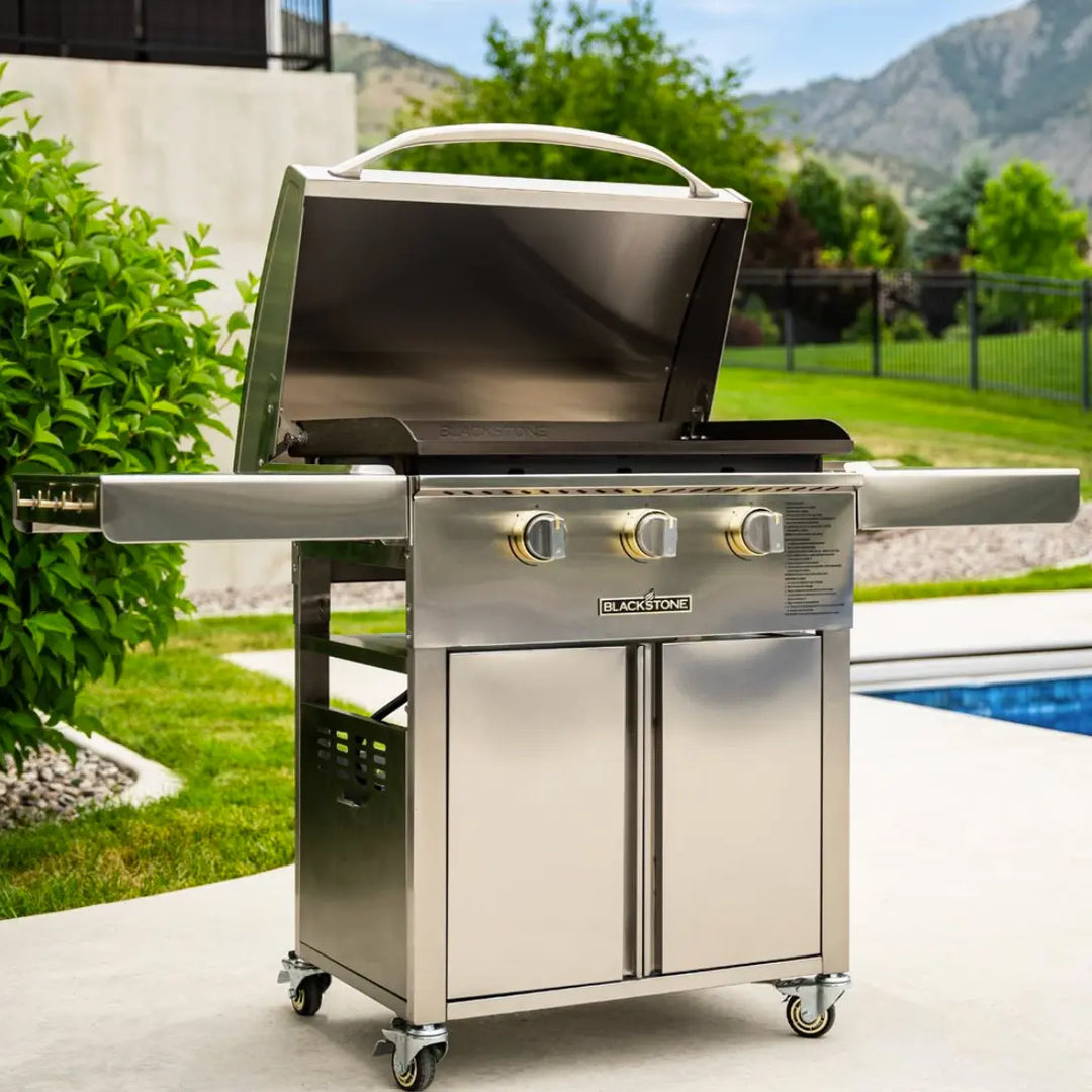 Blackstone Select 28” Griddle with Cabinet, featuring 304-grade stainless steel with brass accents and three independently controlled heat zones for versatile cooking performance.