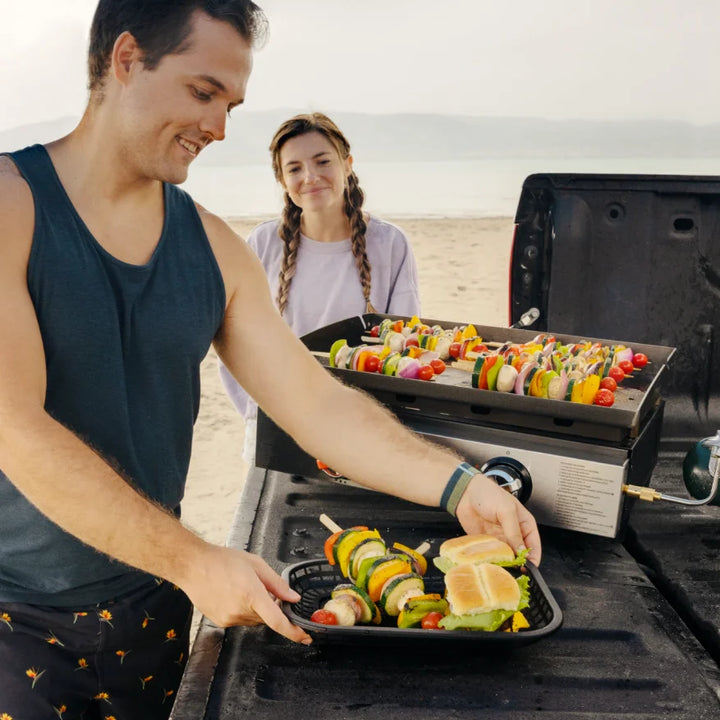Blackstone Original 22-Inch Tabletop Griddle features Omnivore Griddle Plate for even heat distribution, dual stainless steel 'H' burners, and rear grease management system for easy cleanup in portable tabletop design.