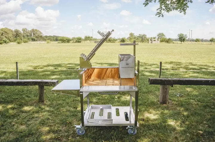 Tagwood Santa Maria Style Clamp Grill with Firebox: Freestanding #304 stainless steel grill with rotating clamp grill, fixed grill box, secondary grate, firebrick-lined walls, and integrated firebox for 360° open-fire cooking experience.