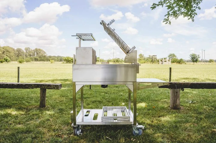 Tagwood Santa Maria Style Clamp Grill with Firebox: #304 stainless steel freestanding grill with rotating clamp grill, fixed grill box, secondary grate, firebrick-lined walls, and integrated firebox for 360° open-fire cooking experience.