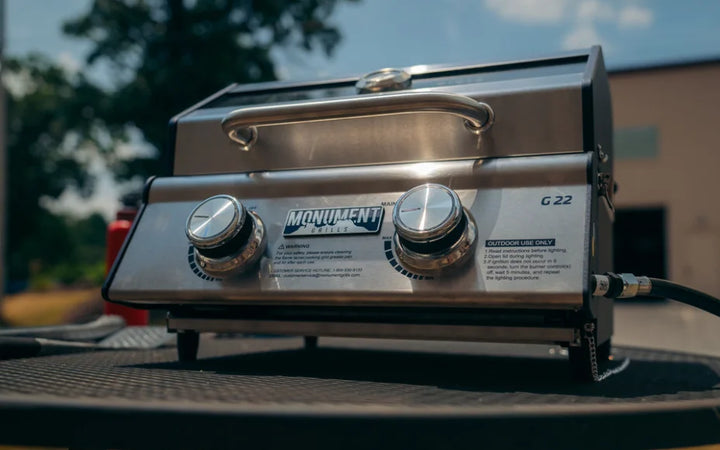 Monument Grills G22 Tabletop Gas Grill featuring compact stainless steel design, dual powerful burners producing 15,000 BTUs, 207 sq in cooking space and portable weight of just 32 lbs.