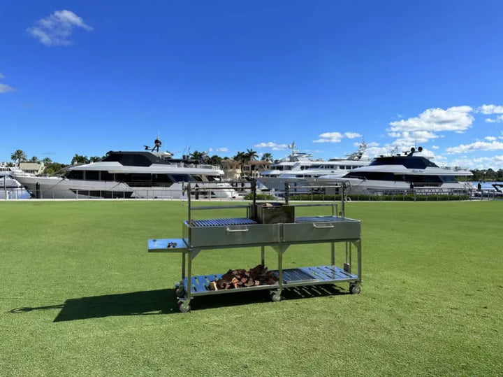 Tagwood XL Santa Maria Style Grill - Stainless Steel: premium 304 stainless steel construction features dual fireboxes, height-adjustable grates, interchangeable griddle, and foldable side table for versatile open-fire cooking.