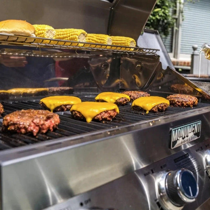 Monument Grills Classic Series Stainless Steel 4-Burner Gas Grill - Propane and Natural Gas Compatible Outdoor Cooking Station with LED Illuminated Control Knobs and ClearView Glass Lid for Precise Heat Control and Restaurant-Quality Seared Meats.