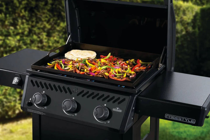 Napoleon 24" Freestyle Non-Stick Griddle features 3 main burners delivering 25,200 BTUs of heat across its 400 sq.in cooking area, with a durable pre-seasoned steel cooktop and folding side shelves for convenient grilling.