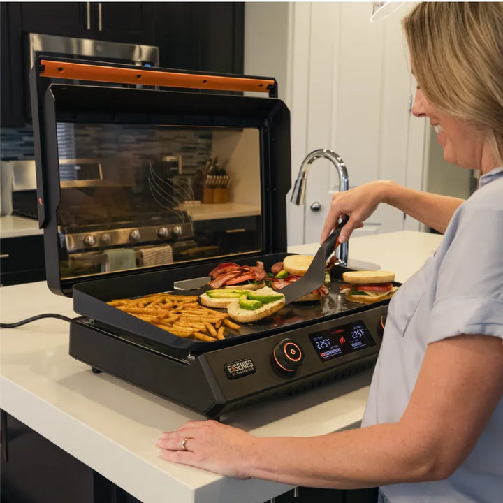 Blackstone E-Series 22-Inch Electric Tabletop Griddle with ceramic titanium-coated cooking surface, dual heat zones, and removable hood for teppanyaki-style cooking.