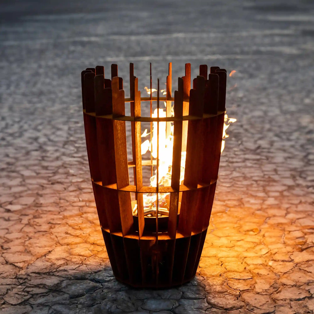 Tall 'Horizon' Fire Sculpture features vertical Corten steel panels wrapped around a bright flame, allowing light to shine through an open slatted design.