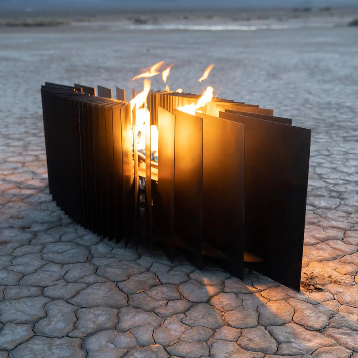 Mobius Fire Sculpture - The Outdoor Plus: A sleek, minimalist design featuring tall flat panels arranged in a wave-like pattern surrounding a bright flame, creating warm light and a modern statement for outdoor spaces.