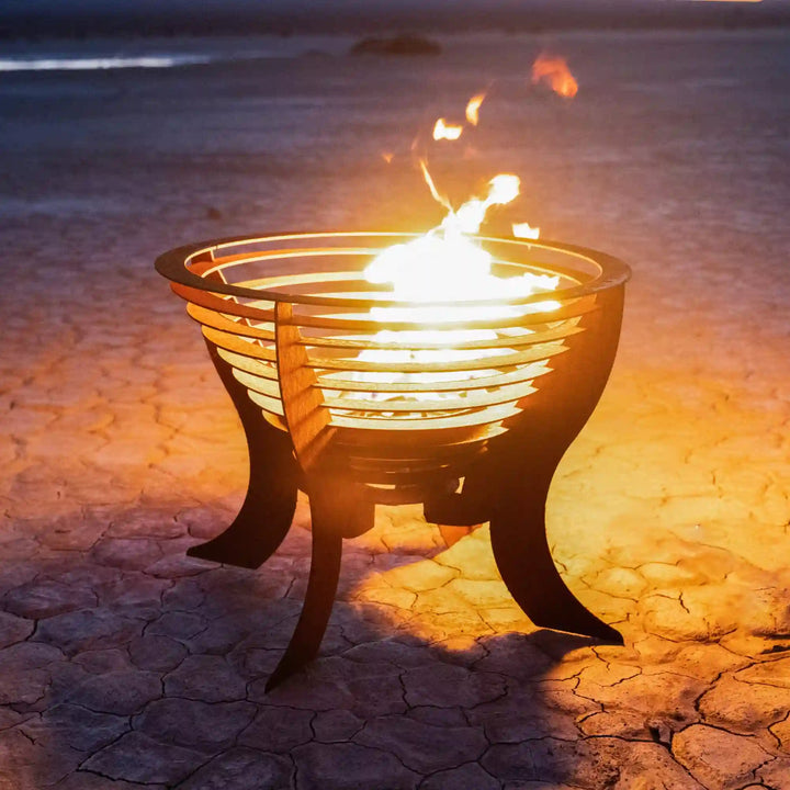 The Saturn Fire Sculpture by The Outdoor Plus features a rounded, layered ring design encircling a vibrant flame, supported by curved legs, exuding warmth and modern style for outdoor spaces.