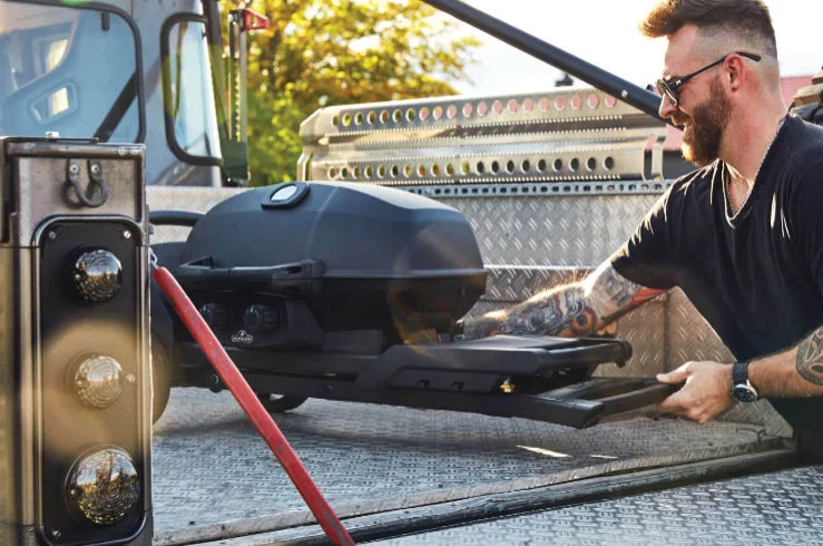 Napoleon Phantom TravelQ PRO 285 Portable Gas Grill with Scissor Cart: Sleek matte black finish wraps lid to cart, featuring high-top lid, two stainless steel burners, removable warming rack, and innovative scissor cart for effortless transport.