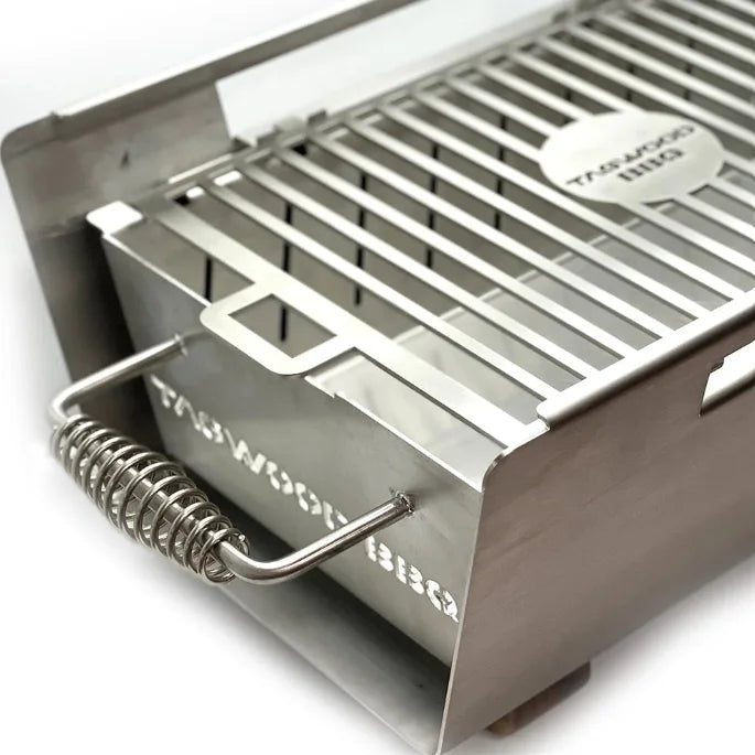 Tagwood Table Top Warming Brazier: A stainless steel and acacia wood design with a warming surface for keeping dishes hot at the table, complete with charcoal drawer, skewers, and safety stop.