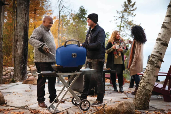 Napoleon TravelQ 285X Portable Propane Gas Grill - Blue/Red: A rugged scissor cart portable grill with dual stainless steel burners, high-top cast aluminum lid, WAVE porcelain-coated cooking grids, and reversible cast iron griddle, ideal for tailgating, camping, or backyard cooking.