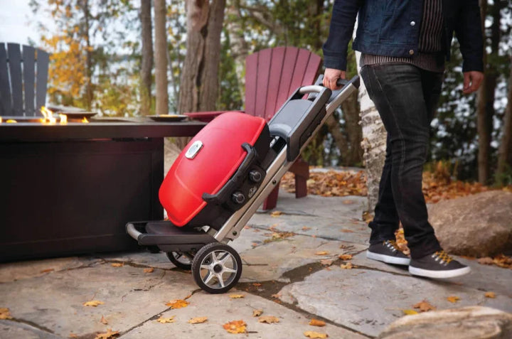 Napoleon TravelQ 285X Portable Propane Gas Grill in bold blue and red design features dual stainless steel burners for precise heat control, rugged scissor cart, and reversible cast iron griddle with WAVE porcelain-coated cooking grids.