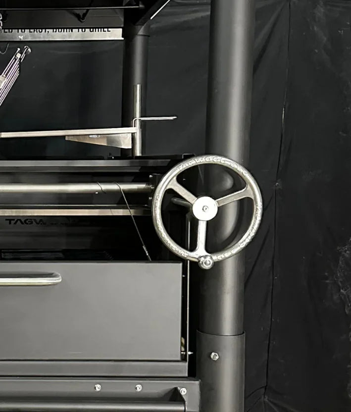 Tagwood "The Beast" Santa Maria Style Grill - Black: A large, all-black steel grill featuring six distinct cooking surfaces, including adjustable grates, clamp grill, swivel grate, griddle, warming rack, and S-shaped meat hooks, with premium 304 stainless steel construction for safe and lasting performance.